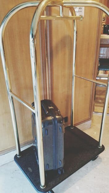 A close-up of a durable, hard-shell suitcase with reinforced corners and a secure TSA-approved lock, sitting on a luggage scale in a well-lit room. The suitcase is stylish and modern.