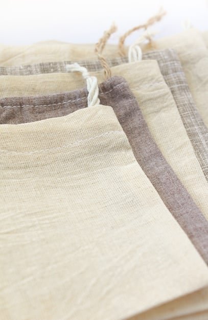 A close-up shot of various sustainable fabrics (organic cotton, recycled polyester, hemp) with tags indicating their eco-friendly properties. The fabrics are neatly arranged and well-lit.