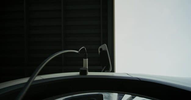 A close-up of an electric vehicle charging port with a charging cable plugged in. The car's logo and design are visible, highlighting its modern aesthetic. The background shows a blurred urban environment.