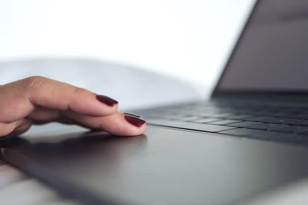A close-up of a laptop's keyboard and trackpad, highlighting the ergonomic design. Blurred in the background is a person working on a spreadsheet, emphasizing productivity and comfort for remote work.