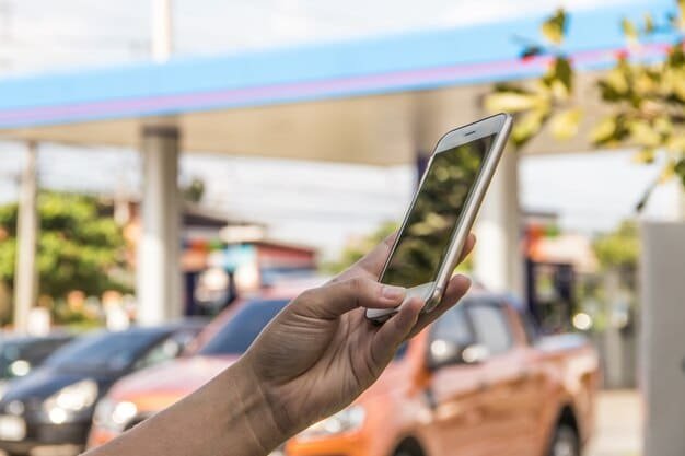 A smartphone displaying a gas price app, showing prices for gas stations along a highway. A credit card and a set of car keys are beside the phone.