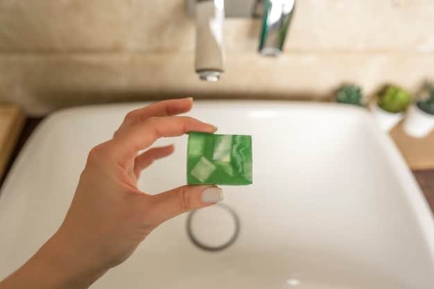 A close-up shot of a hand pouring eco-friendly dish soap into a sink full of water. The dish soap has a clear, natural appearance with a subtle green tint. The background shows dirty dishes partially submerged in soapy water.